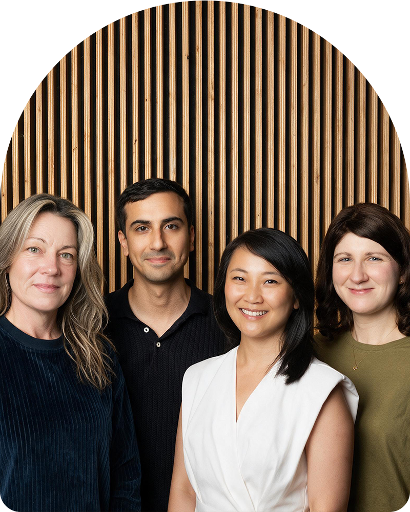 Group portrait of the four Inner Room therapists standing together in front of a wooden slat wall